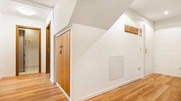 A hallway with wooden flooring, white walls, and a door with a wooden frame.