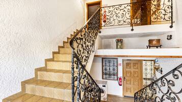 A staircase with ornate metal railings, a wooden door, and a washing machine in the background.