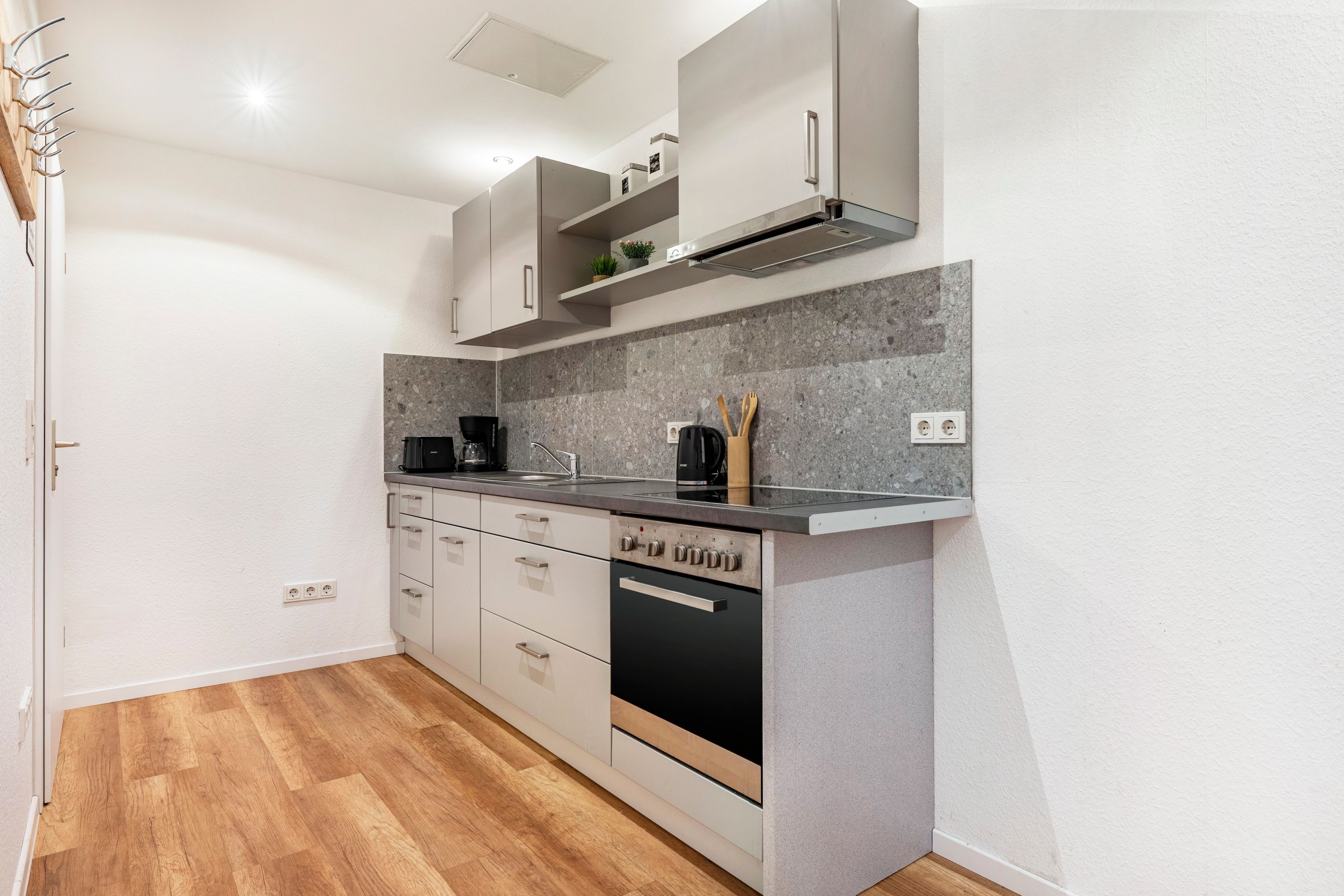 A modern kitchen with a built-in oven, a coffee machine, and a sink.