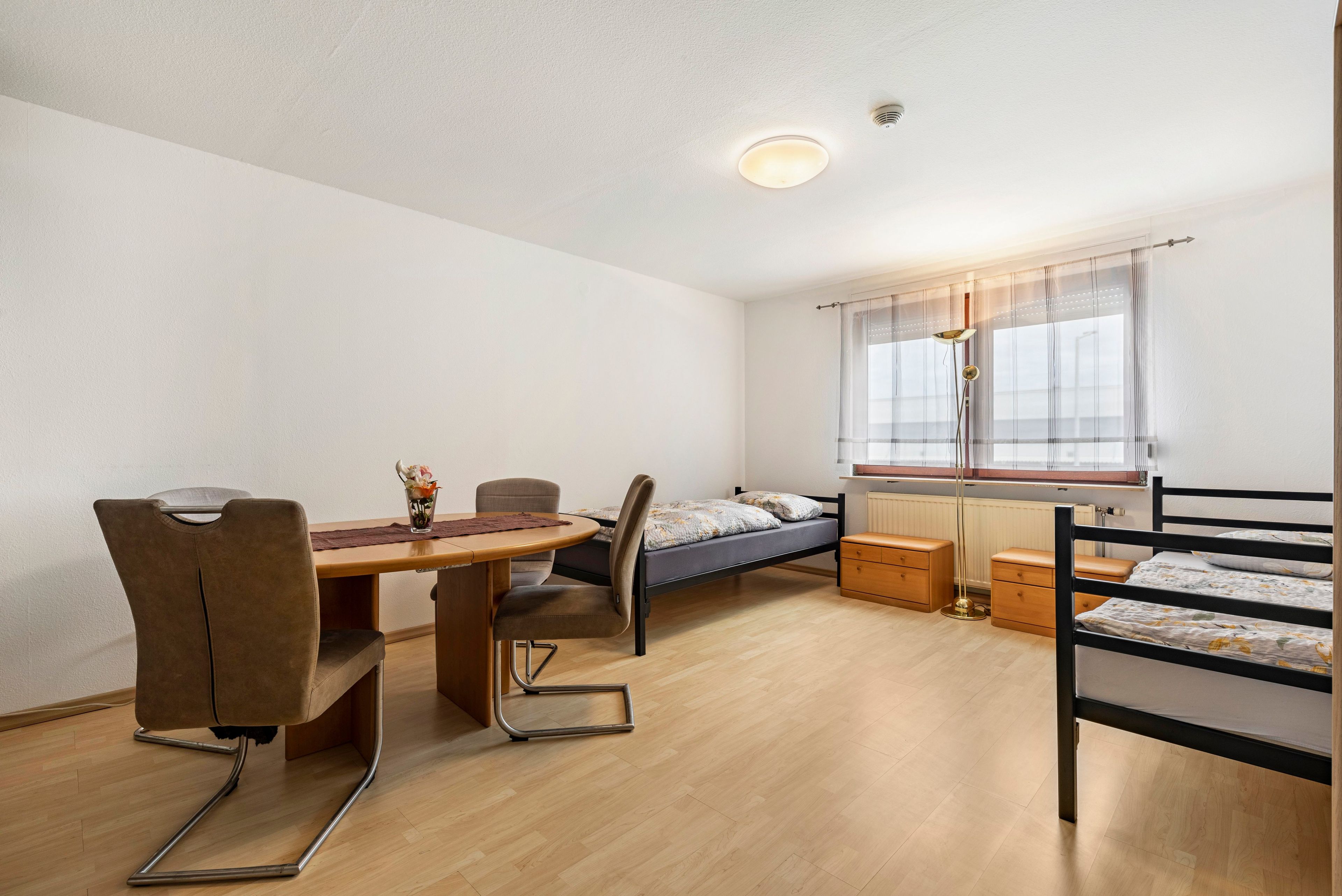 Ein kleines Zimmer mit Bett, Schreibtisch und Stuhl.