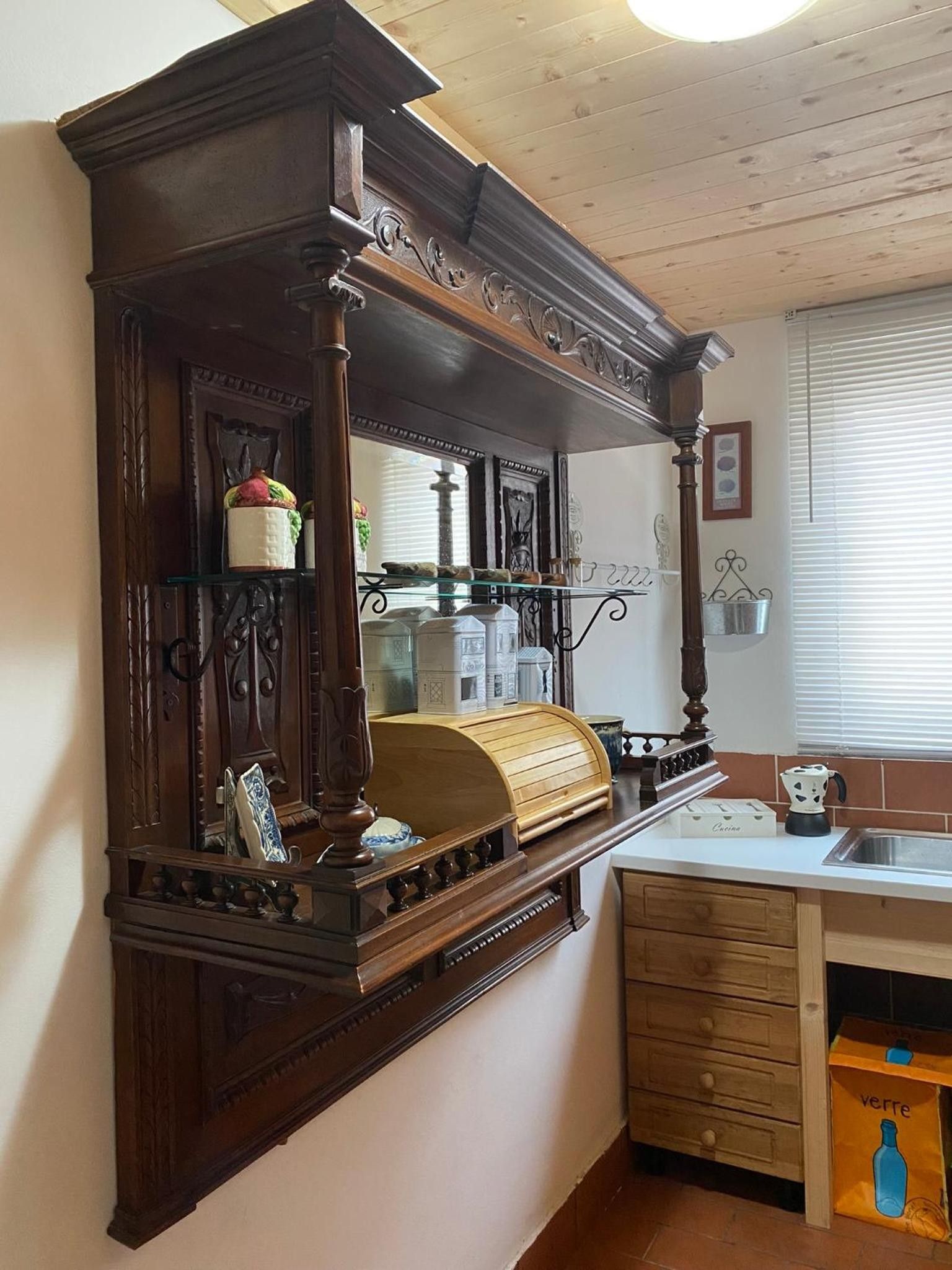 Eine Küche mit einem Holzkasten, einer Spüle und einem Fenster mit Jalousien.