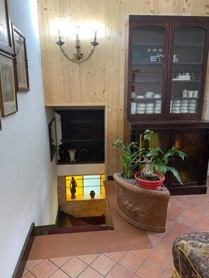 A living room with a fireplace, a cabinet with dishes, and a potted plant. - Viale del Re 33: Your Vintage Retreat Steps from the Sea in Catona (RC) (Reggio Calabria)