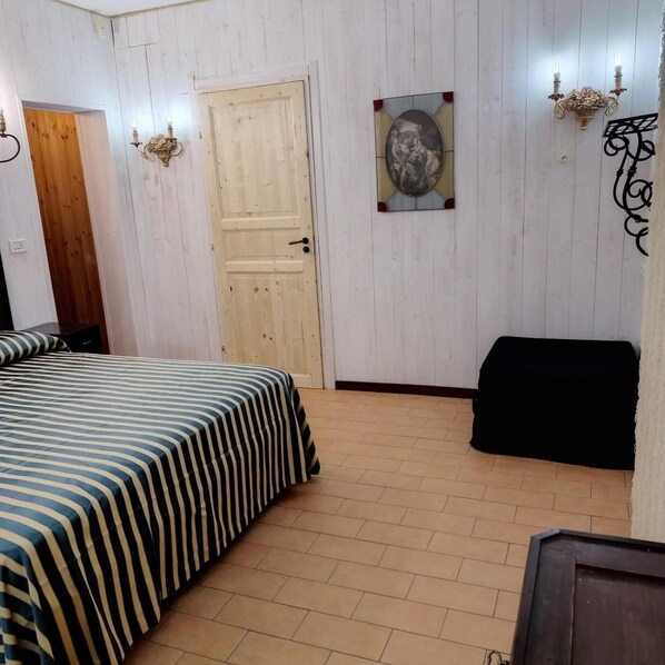 A room with a bed, a door, a wall-mounted picture, and a bench.