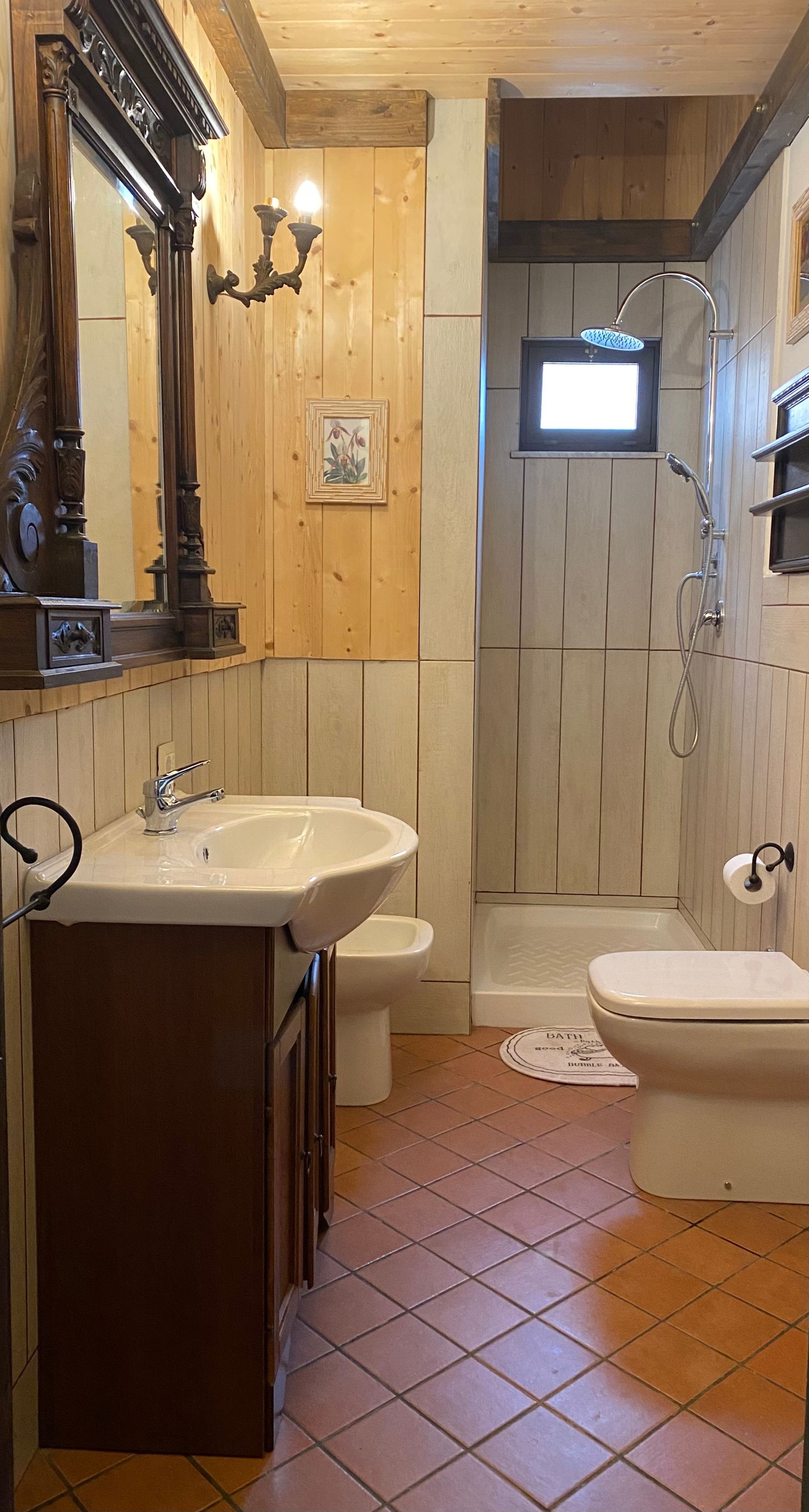Ein Badezimmer mit einem Holzkosmetikschrank, einem Waschbecken, einer Toilette und einer Duschkabine.