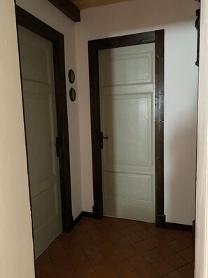 A hallway with two closed doors, a tiled floor, and a wall with a dark trim.