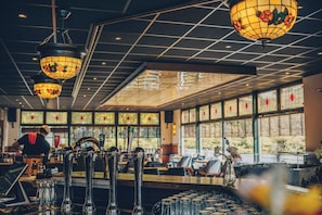 Un espace bar doté de plusieurs robinets, d’un comptoir et de lampes suspendues ornées de motifs floraux.