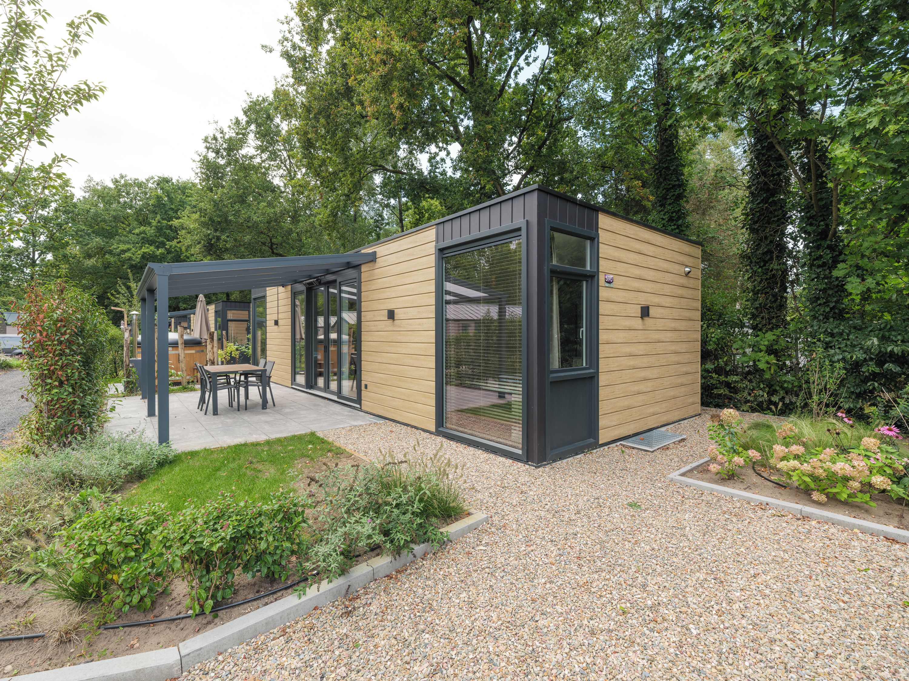 Una moderna area patio esterna con una pergola, posti a sedere e un giardino con vialetti in ghiaia.