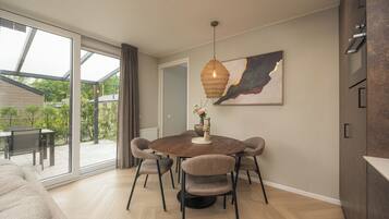 Een moderne eethoek met een ronde tafel, zes stoelen en een hanglamp.