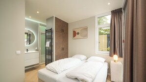 Quarto moderno com cama, mesa de cabeceira e janela com cortinas.