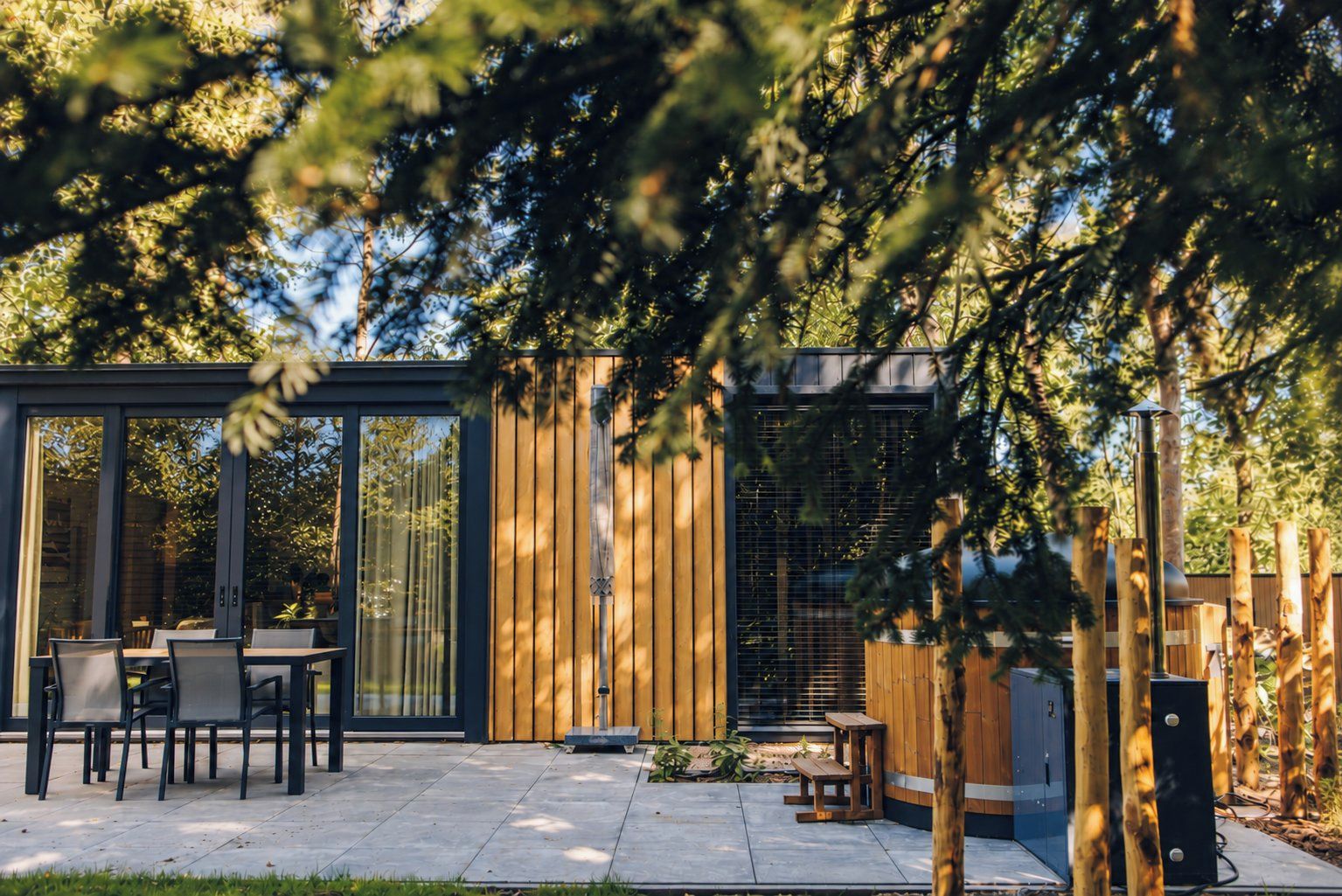 Une terrasse extérieure moderne comprenant un espace repas, une clôture en bois et un barbecue.