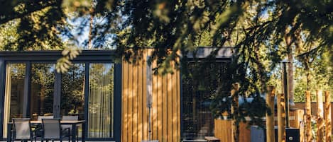 A modern outdoor patio with a dining area, a wooden fence, and a grill.