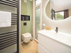 Une salle de bain moderne avec des toilettes, un lavabo et un miroir.
