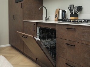 A modern kitchen with wooden cabinetry, a built-in dishwasher, and a coffee maker on the countertop.