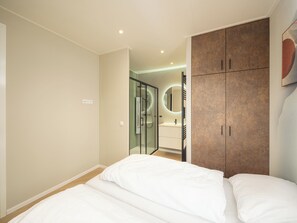 A bedroom with a bed, a wardrobe, and a bathroom visible through a glass door.