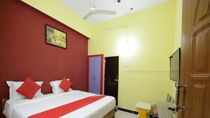 A bedroom with a bed, a wardrobe, a mirror, and a ceiling fan. - Hotel O Vellore Formerly SP Highway Inn (Vellore)