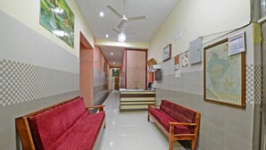 A hallway with two red benches, a reception desk, a ceiling fan, and a map on the wall. - Hotel O Vellore Formerly SP Highway Inn (Vellore)