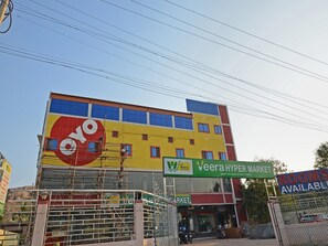 En bygning med flere etager, med et stort, gult og rødt skilt for 'Oyo' og et grønt skilt for 'Veera Hyper Market'.
