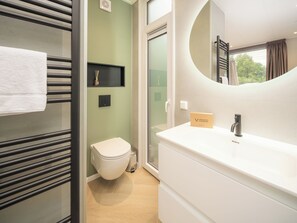 Ein modernes Badezimmer mit Toilette, Waschbecken und Spiegel.