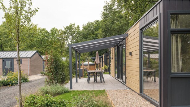 Uma área de estar ao ar livre moderna, com pérgola, assentos e jardim.