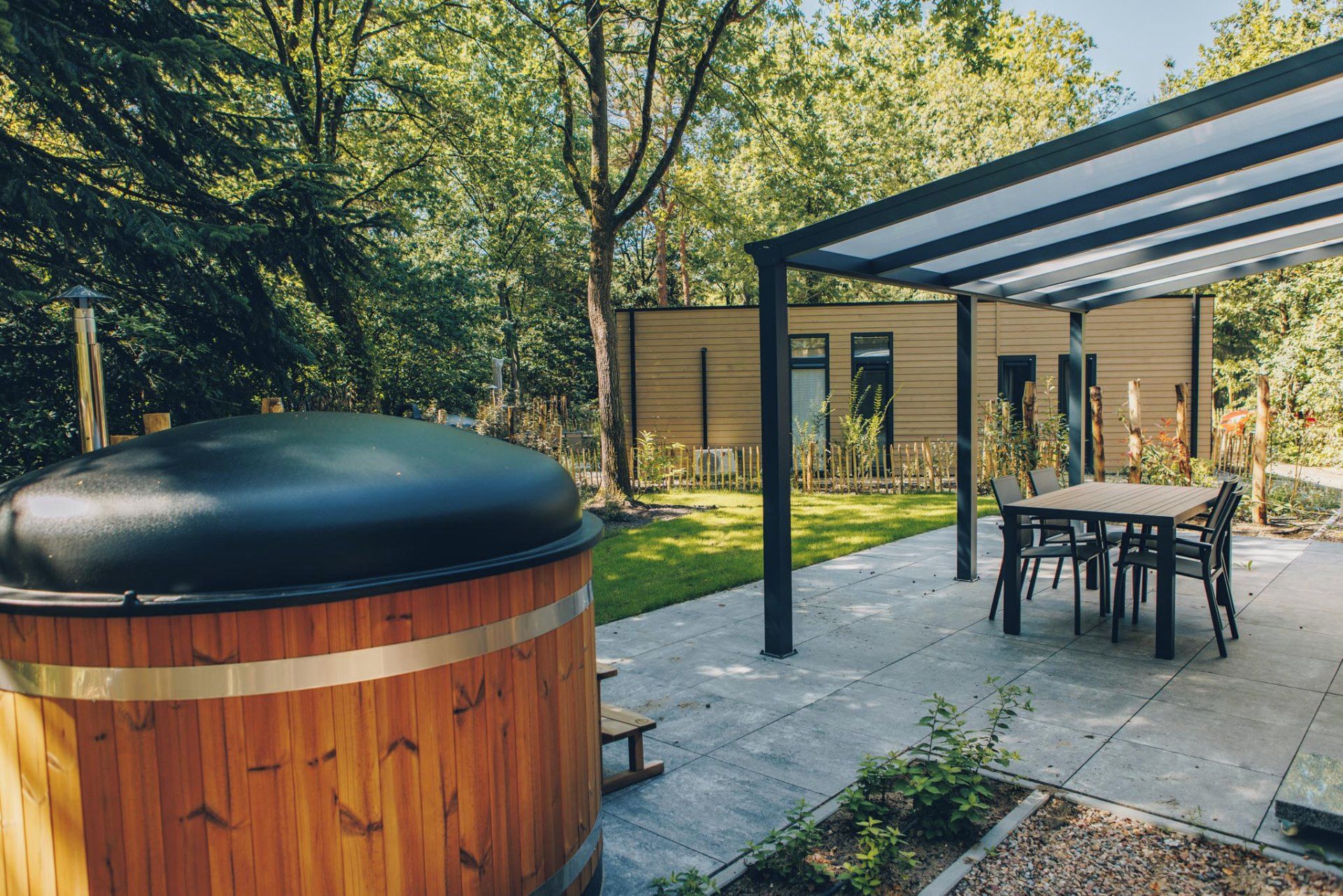 A covered outdoor patio with a wooden barrel, a table, and chairs.