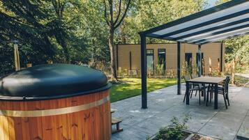A covered outdoor patio with a wooden barrel, a table, and chairs.