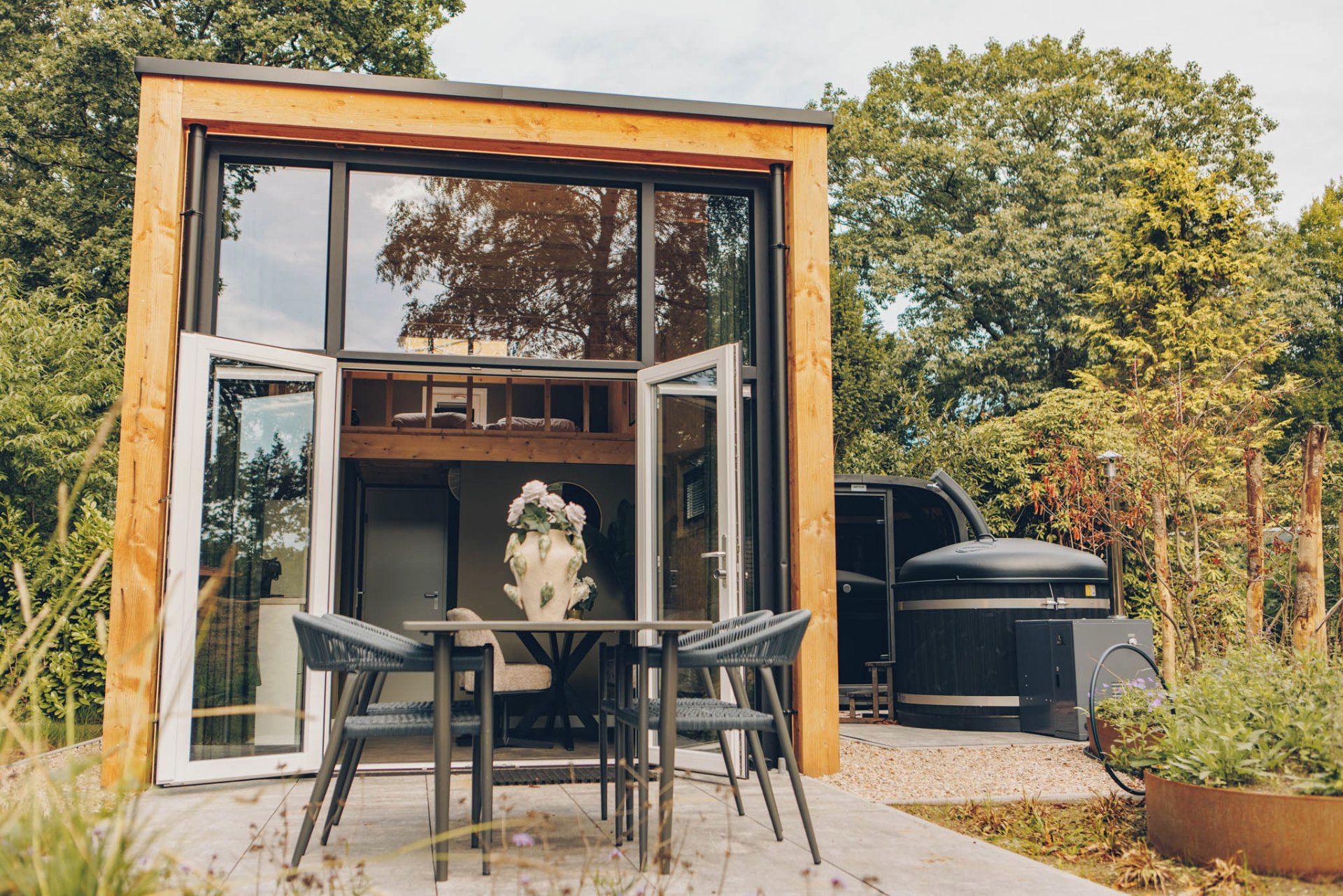 A modern, glass-enclosed structure with a dining area featuring a table and chairs.