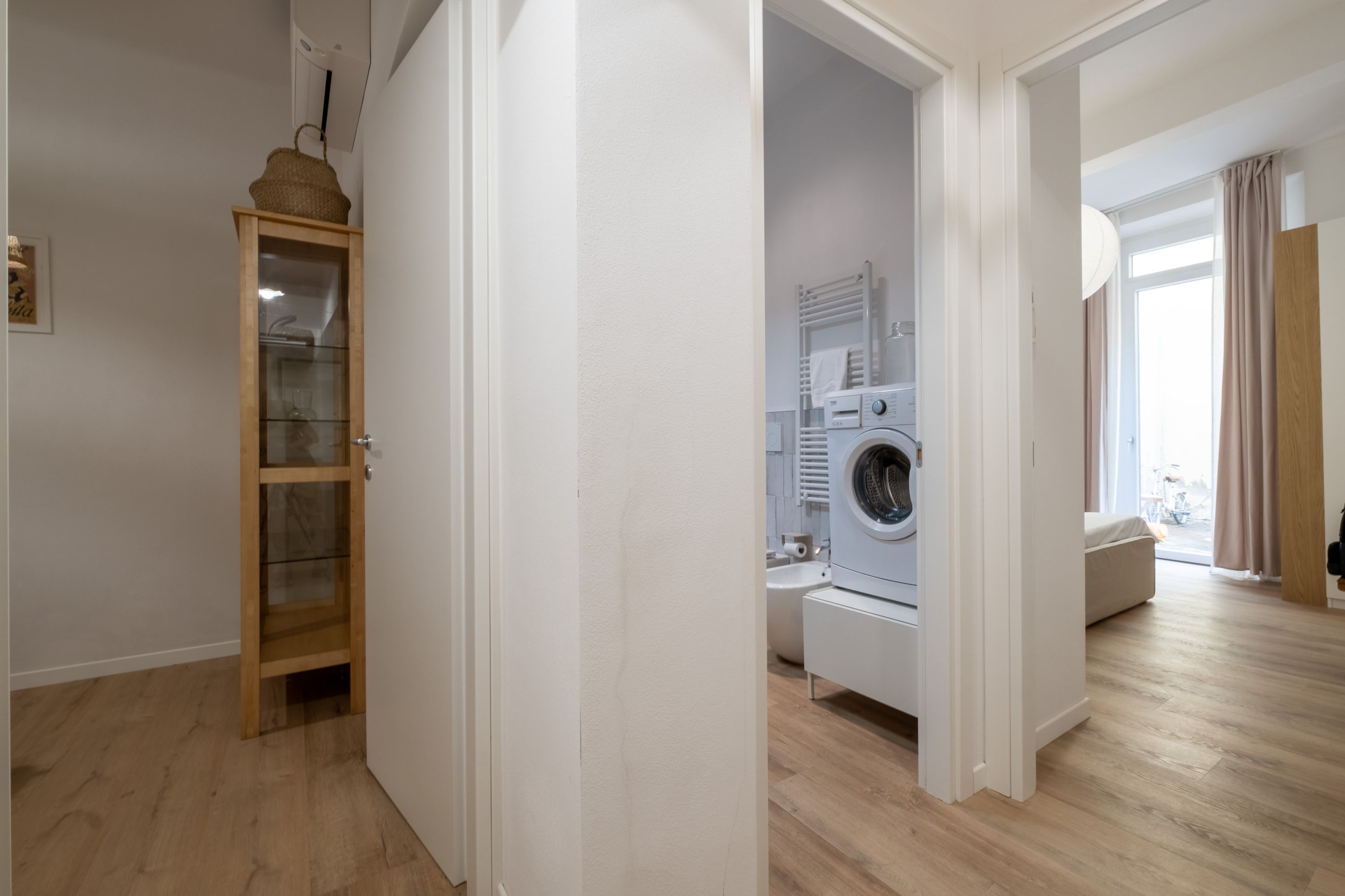 Eine moderne Wohnung mit Holzschrank, Waschmaschine und Blick auf die Straße.