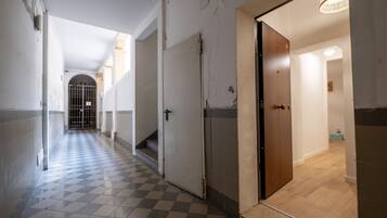Un corridoio con pavimento a scacchi che conduce a una porta in legno.
