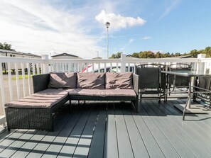 Eine Terrasse mit einer Rattan-Couch, Metallstühlen und einem Tisch.