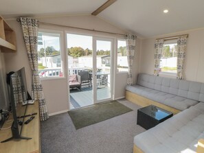 A living room with a sofa, a television, a sliding glass door leading to an outdoor area, and a small table. - 10 Gosling (Scarborough)