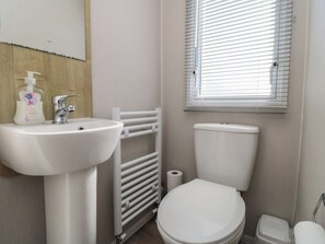 Ein Badezimmer mit weißem Waschbecken, WC und Heizkörper.