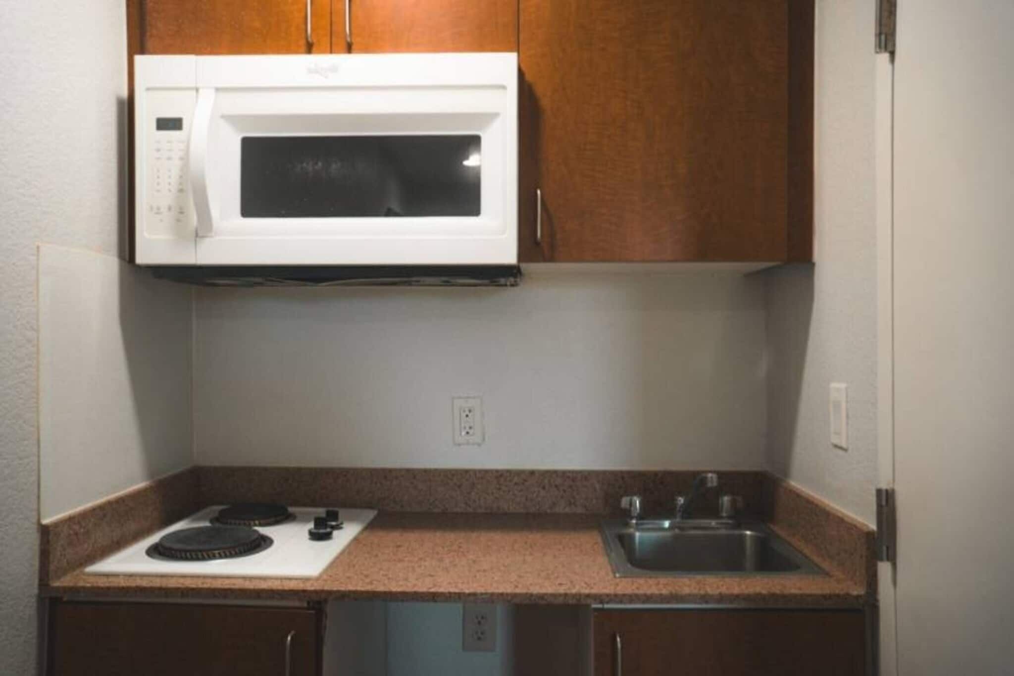 A compact kitchen with a microwave, stove, and sink.