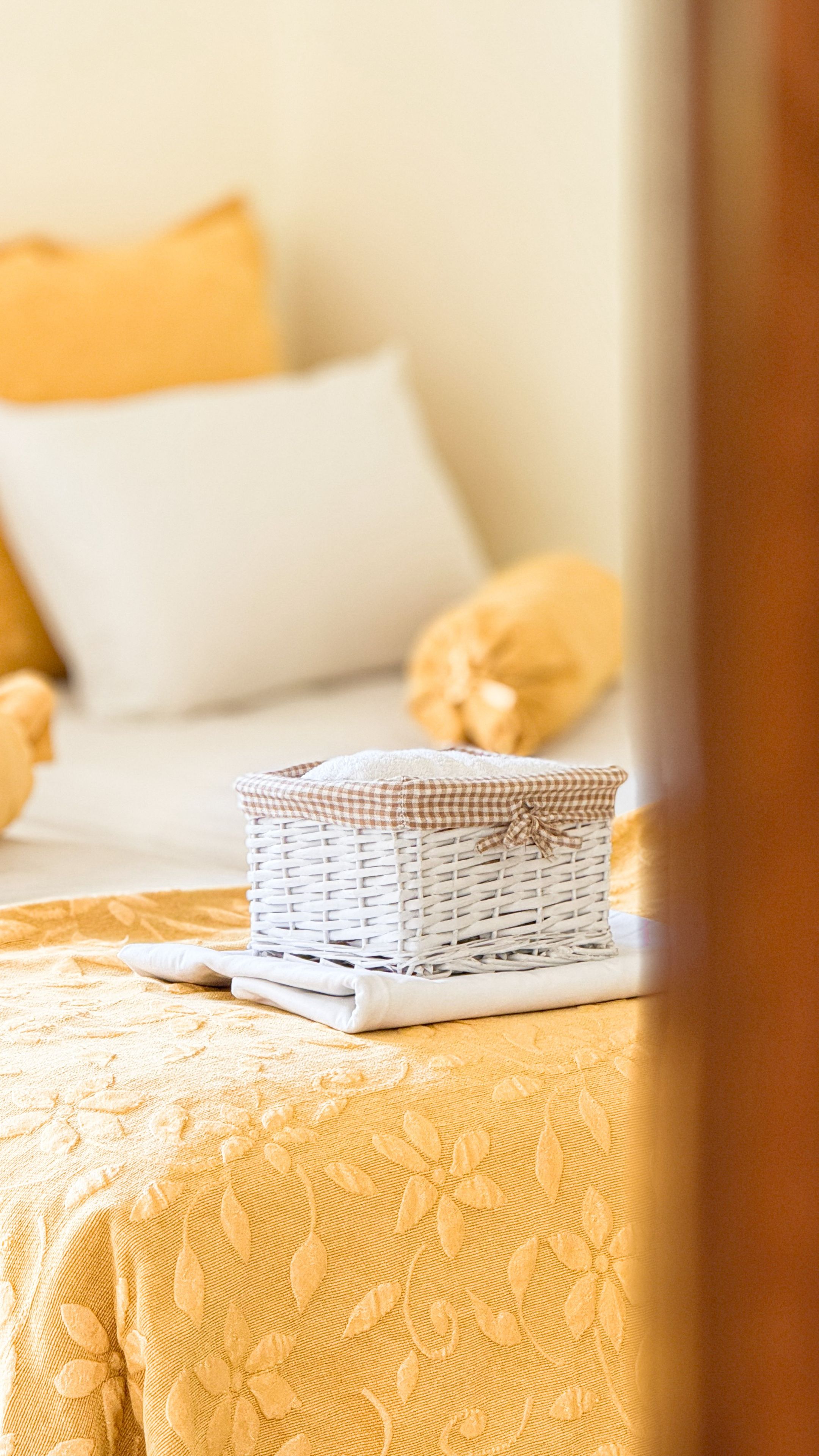 Un lit avec un oreiller blanc et un panier à carreaux posé dessus.