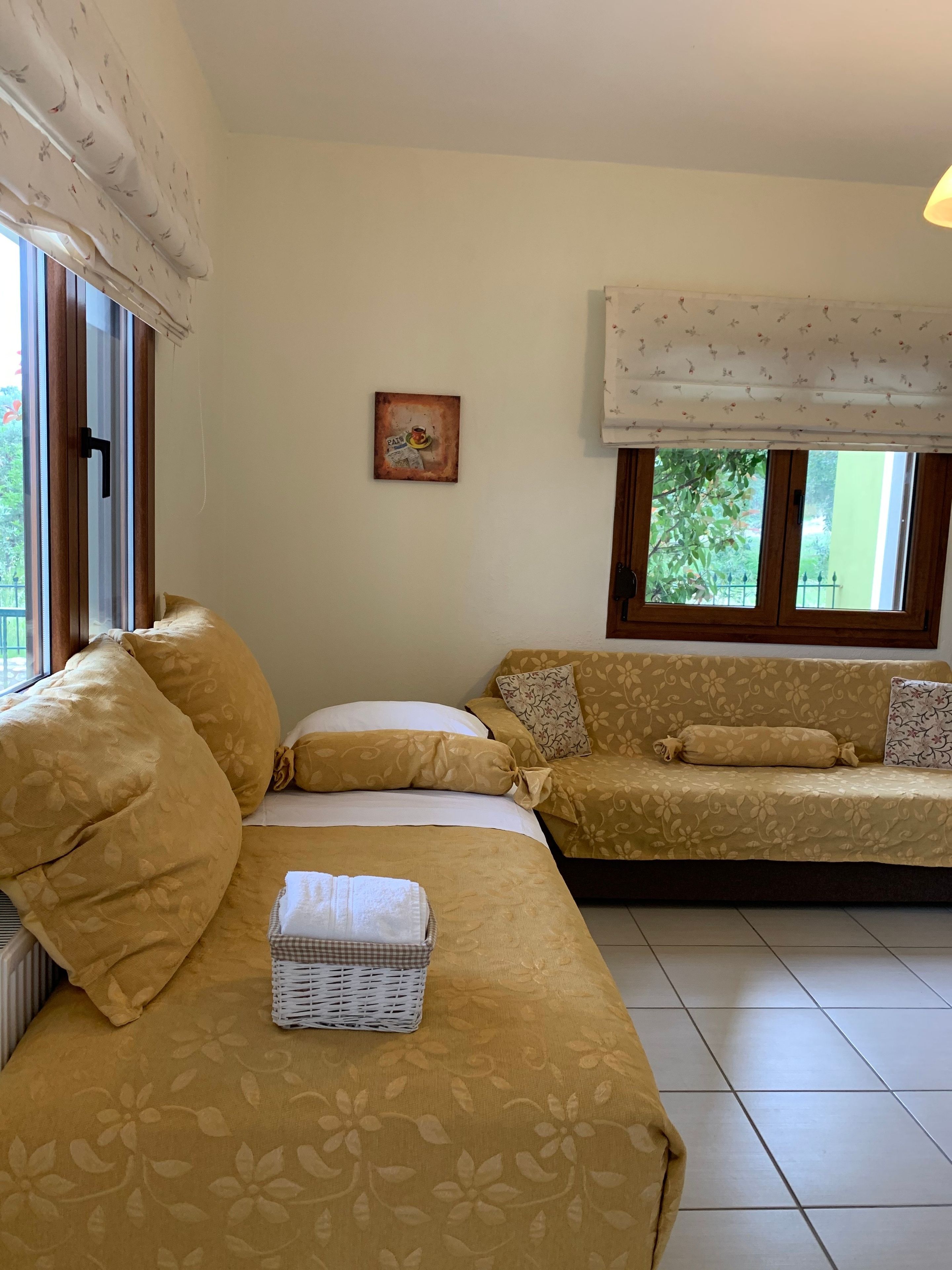 Ein Zimmer mit einem Bett, einem Sofa, einem Fenster mit Blick auf Grünflächen und einem Wandbild.