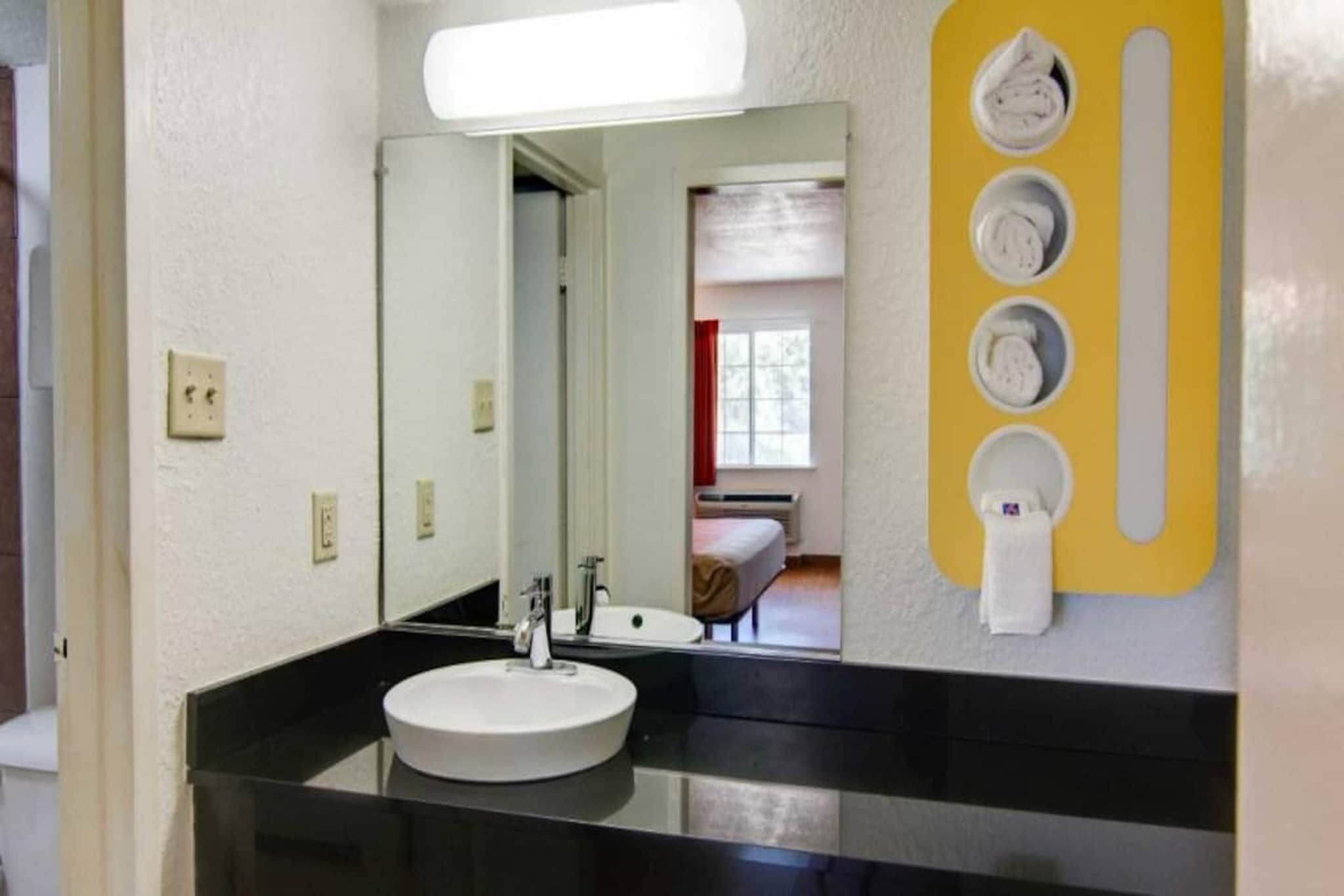 Een badkamer met een wit wastafel, een spiegel en een gele handdoekdispenser.