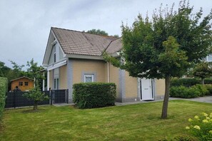 A residential house with a tiled roof, a front door, and a small front yard with a tree and a hedge. - Holiday paradise sea air (Kamperland)