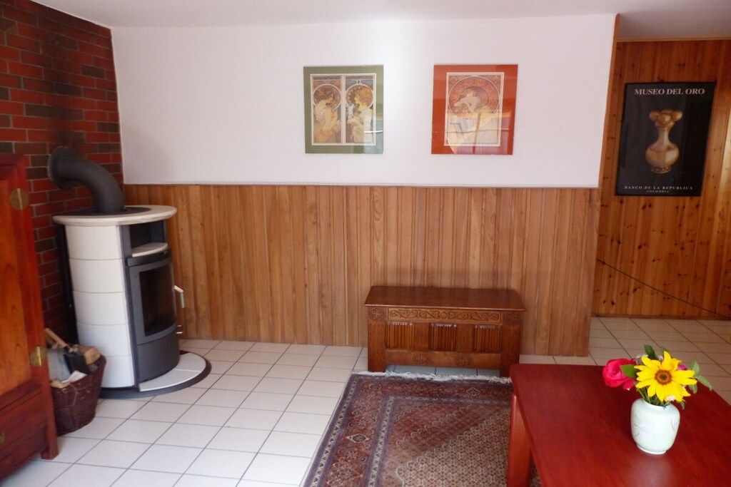 Une pièce avec un mur lambrissé en bois, une cheminée, un banc, un tapis et une affiche du Museo del Oro.