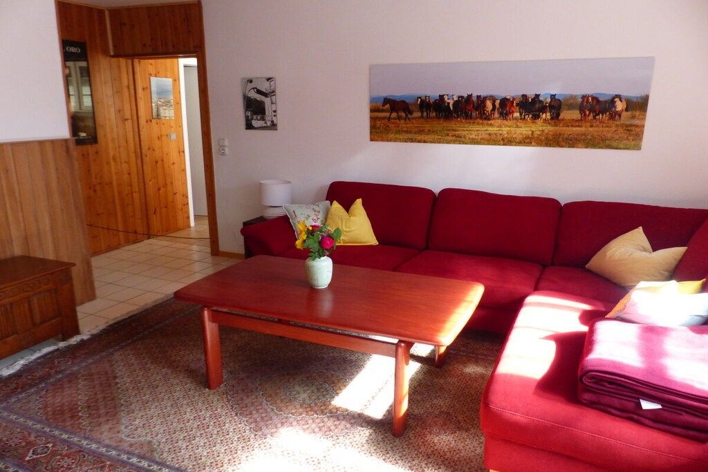 A living room with a red sofa, a wooden coffee table, and a rug.