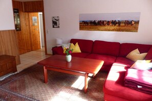 Ein Wohnzimmer mit einem roten Sofa, einem Holztisch und einem Teppich.