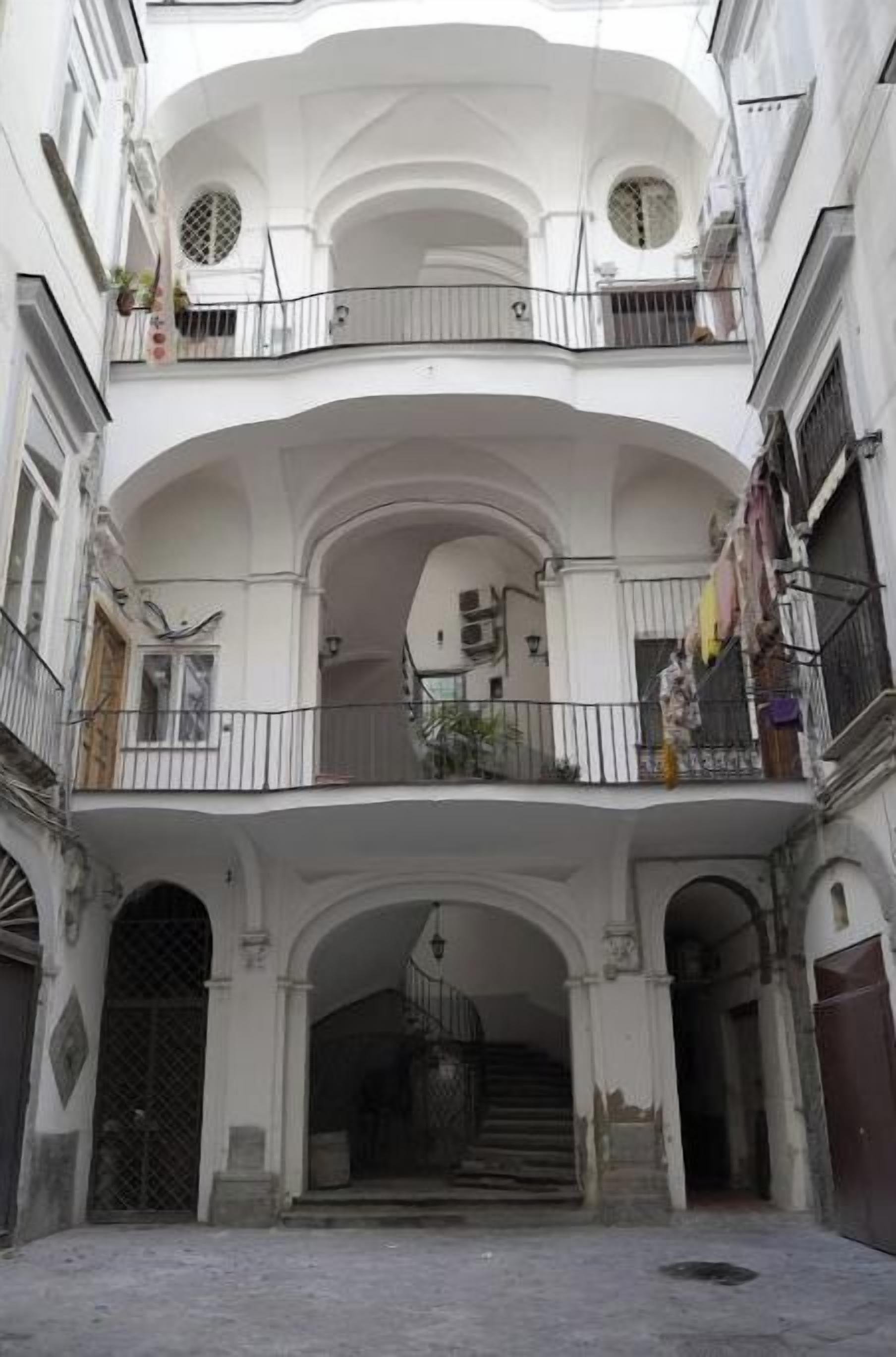 A multi-story building with a central courtyard, balconies, and a staircase leading to an upper floor.