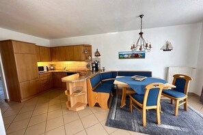 Een compacte keuken met houten kastjes, een inbouwbank en een eettafel met stoelen.