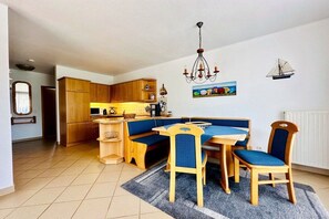 Eine kleine Küche mit Holzausstattung, einem Esstisch mit blauen Stühlen und einer Kronleuchter.