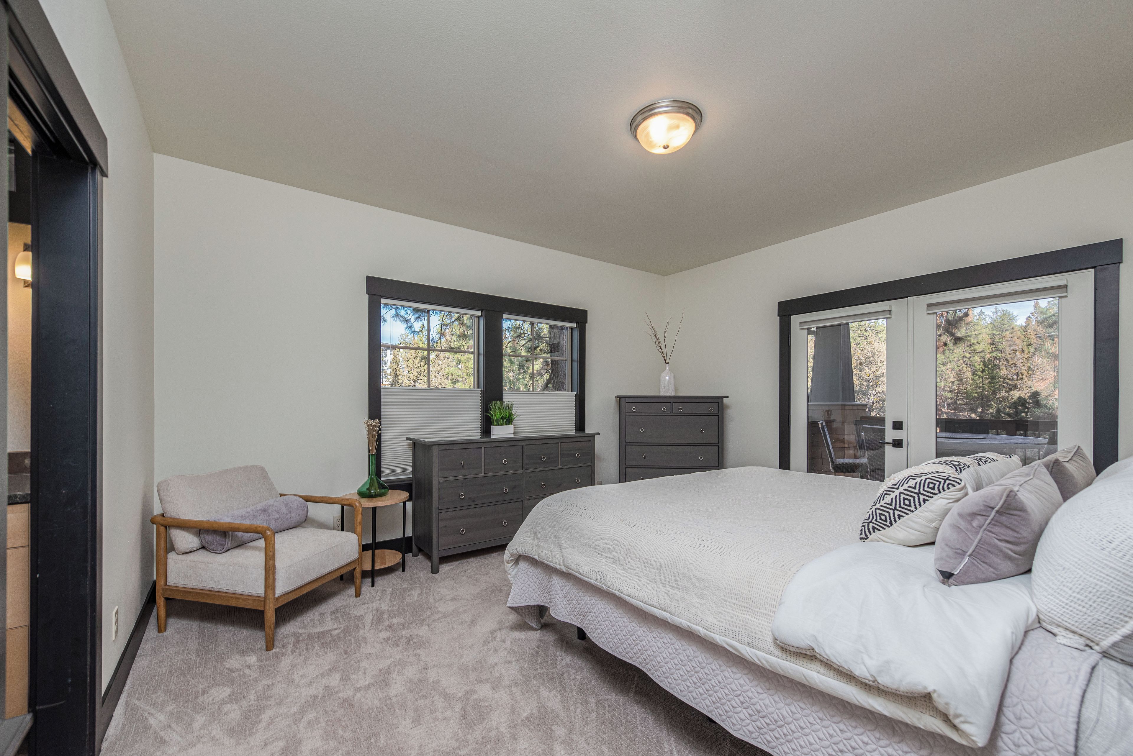 A bedroom with a bed, dresser, chair, and a window with blinds.
