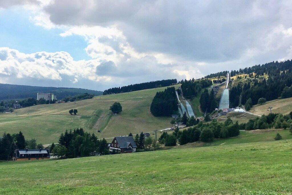 Ländliche Landschaft mit Brücke, Häusern und Hügel.