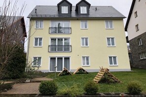 Ein mehrstöckiges Wohngebäude mit Flachdach, Balkonen und einem gepflegten Rasen.