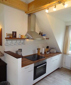 A kitchen with a wooden countertop, white cabinets, a built-in oven, and a hanging light fixture. - Holiday apartment with 2 bedrooms (Kurort Oberwiesenthal)