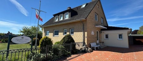 Un bâtiment en briques de deux étages, orné d’un mât pour drapeau, d’une enseigne et doté d’une allée pavée.