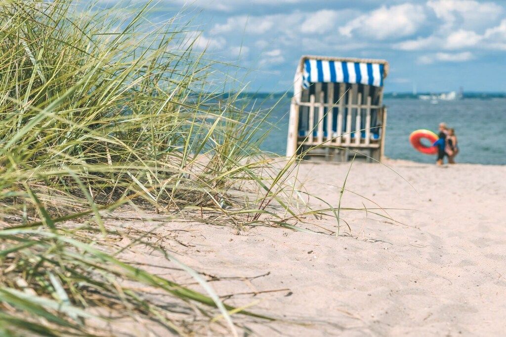 Une plage avec une chaise de plage à rayures et un bouée de sauvetage en arrière-plan.