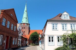 Eine schmale Straße mit traditionellen Gebäuden, eines davon mit einem markanten, grünen Turm.