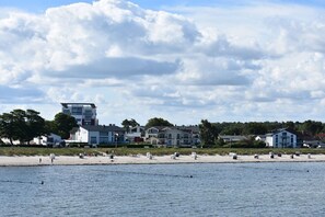 A coastal view with a beach, buildings, and a cloudy sky. - Holiday apartment in Glowe with swimming pool (Glowe)